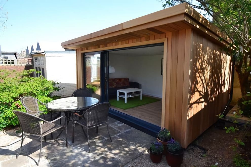 Exterior of a garden room. Large sliding doors open onto a patio area