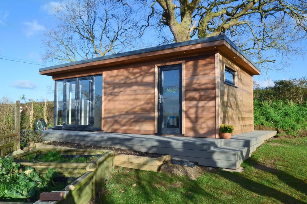 Exterior of a garden building with shower and kitchenette. The UPVC doors and casement windows are coloured anthracite grey. The building clad with Western red cedar TGV cladding boards