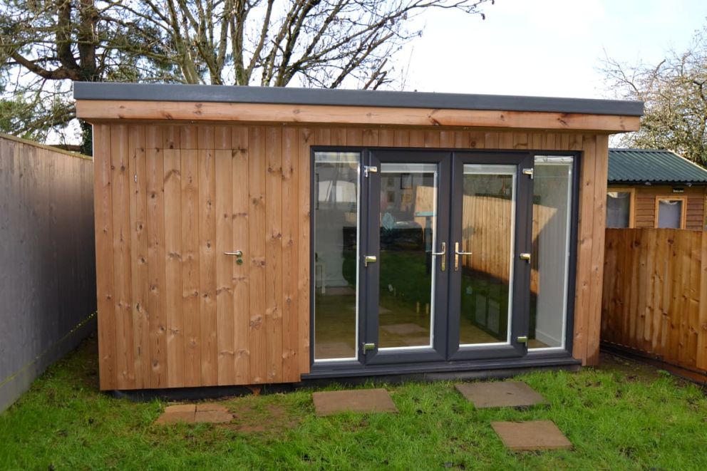 Garden room with sidestore. Image shows Thermowood cladding and UPVc French doors with sidelights. The door to the side room is concealed with Thermowood cladding