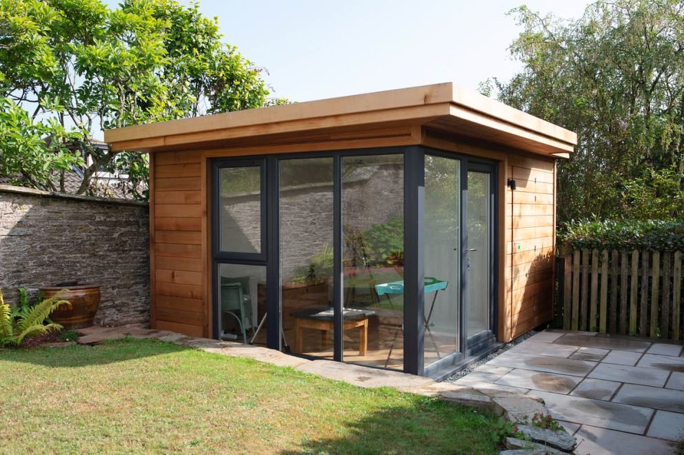 A garden studio with attached storeroom in Chillington. This view shows the front glazed patio doors, with the discrete side door