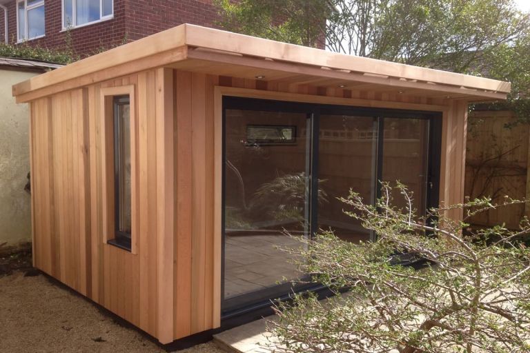 Finished garden room with exterior cladding. Large sliding doors lead onto a patio area