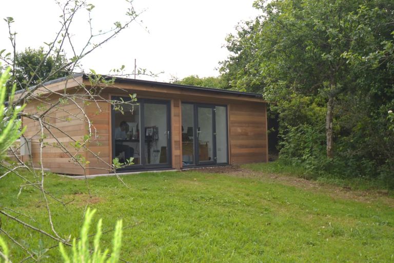 Rear view. Large windows overlook an area laid to lawn