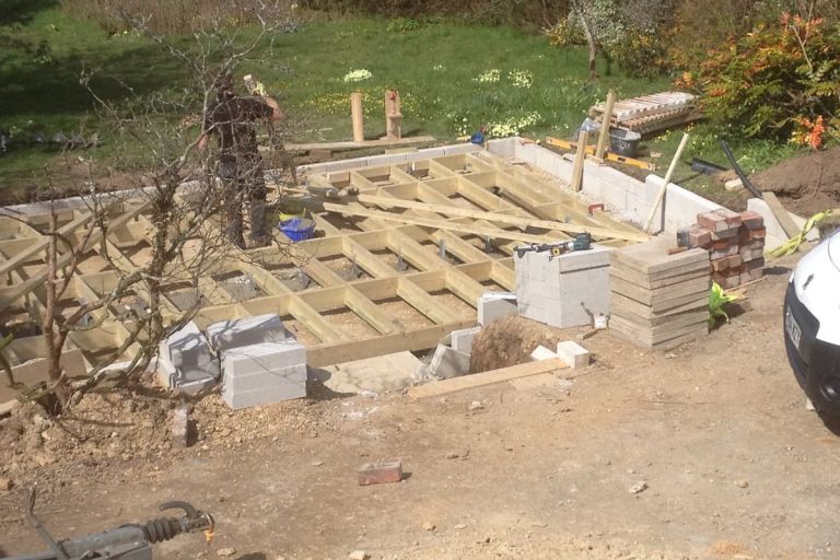 Image shows the timber frame for the flooring and the concrete block retaining walls with steps down to office building