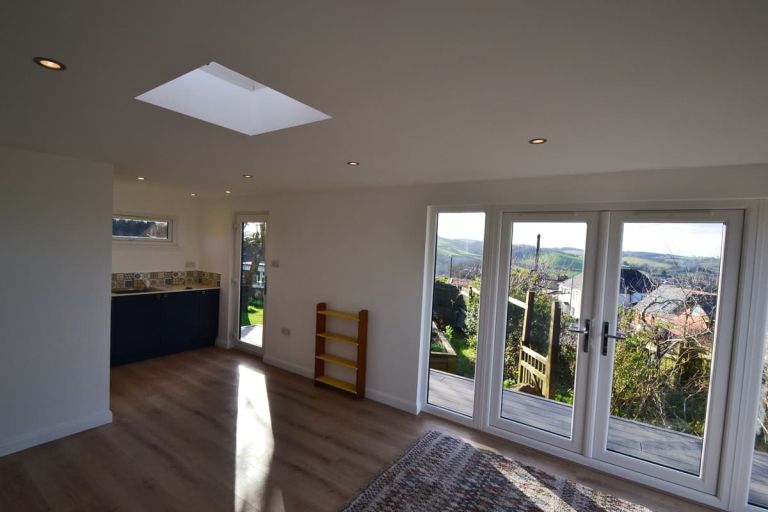 Interior of the garden room. View from the main area with kitchenette off to side. Views through the UPVc windows which are coloured white on the inside