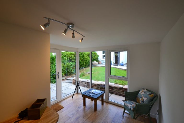 View of the glazed end of the garden room, from the inside, showing the garden and house beyond