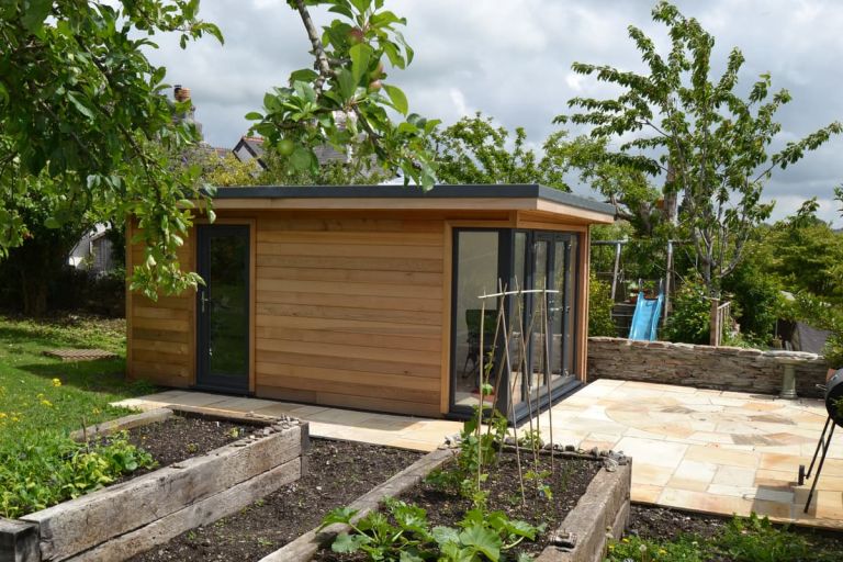 A writer's retreat garden room, shown from the side with the door to the attached storage room